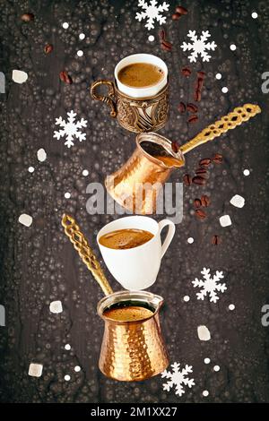 Balancierung der Pyramide aus Jezves, türkischen Kaffeekannen und Tassen auf dunklem Hintergrund mit Kaffeebohnen und Zucker. Stockfoto