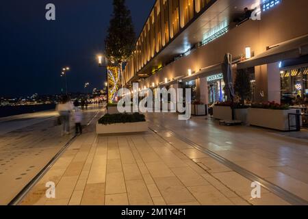 Eine Wand ist mit weihnachtsdekorationen bedeckt. Fußweg vor luxuriösen Geschäften und Cafés. Nachtgang-Konzept. Stockfoto