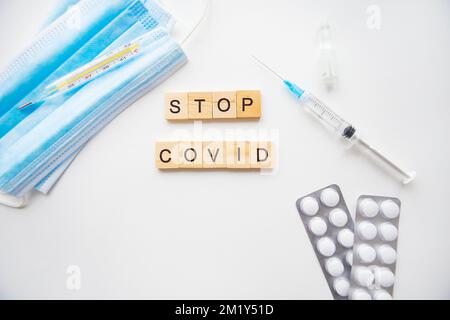 Stoppen Sie die Inschrift des Coronavirus. Vorbereitung für die Impfung gegen covid-19. Spritze, Impfstoff, Pillen, medizinische Maske Stockfoto