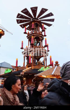 Hanau, Deutschland - 15. Dezember 2019: Großer Pyramidenspinner mit Kerzen und Menschen auf einem Stand auf einem Weihnachtsmarkt in Hanau, Deutschland. Stockfoto