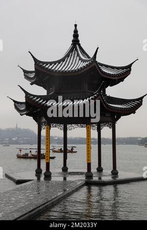 Eine vertikale Aufnahme des chinesischen Pavillons am Westsee mit kleinen Booten während des Tages in Hangzhou, Ostchina Stockfoto