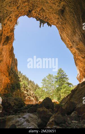 Eine große Höhle unter einer großen Felsformation mit Blick auf den blauen Himmel. Stockfoto