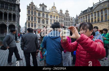 20151127 – BRÜSSEL, BELGIEN: Abbildung zeigt eine Touristin, die am Grote Markt am Freitag, den 27. November 2015, in Brüssel ein Foto mit ihrem Smartphone und einer Titelseite des Eiffelturms macht. Die terroristische Bedrohung ist nach sechs Tagen wieder auf Stufe drei, in der Region Brüssel, und wird für den Rest des Landes auf Stufe drei gehalten. BELGA FOTO BENOIT DOPPPAGNE Stockfoto