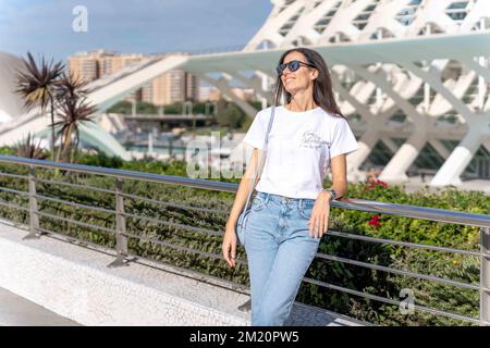 Brünette Frau in weißem T-Shirt und Jeans, die draußen posiert Stockfoto