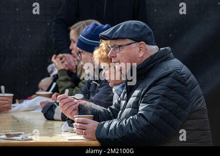 Menschen, die Fischsuppe auf der traditionellen Ostsee-Heringsmesse oder im Stadin silakkamarkkinat in Helsinki, Finnland, essen Stockfoto