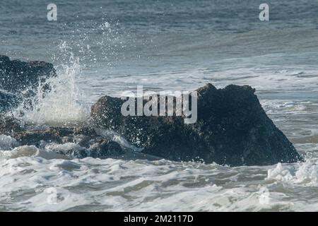 Dann spritzt Wasser in der Nähe der großen Steine an der Küste von Santa Clara del Mar, Buenos Aires, Argentinien Stockfoto