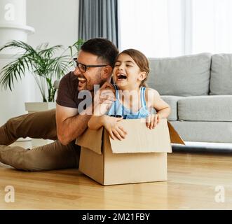 Kind Familie Vater Spaß glücklich Mädchen Glück Tochter Box zusammen Umzug Umzug Karton Stockfoto