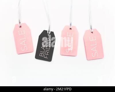 Rosafarbene und schwarze Tags auf weißem Hintergrund. Glamouröse Etiketten auf silbernen Fäden. Black-Friday-Angebote und -Einkäufe. Draufsicht, flach liegend. Stockfoto