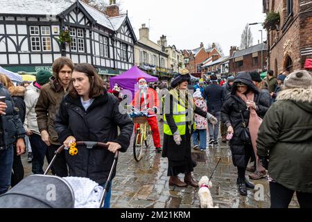 Der Weihnachtsmann auf einem Fahrrad versucht, beim Lymm Dickensian Festival 2022 durch die Menschenmassen zu fahren Stockfoto