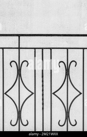 Schwarzes geometrisches vertikales Element aus Metall, dekoratives Stahlzaundesign mit hellweißem Wandhintergrund. Stockfoto
