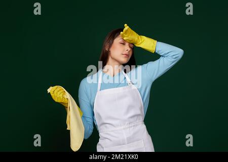 Müde Frau in gelben Handschuhen und sauberer Schürze Stockfoto