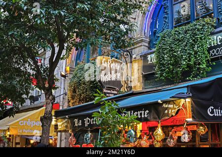 Paris (Quartier Latin), Frankreich - November 9. 2022 Uhr: Wunderschönes farbenfrohes, altes romantisches Oldtimer-Restaurant am Abend, grüne Bäume und Pflanzen, Markise Stockfoto