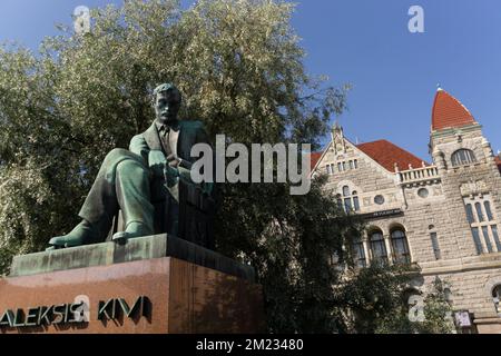 Aleksis Kivi-Statue vor einem grünen Baum mit dem nationaltheater von helsinki im Hintergrund Stockfoto