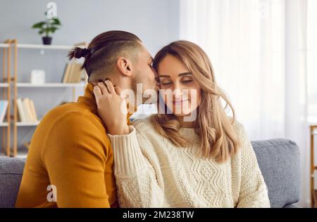 Porträt eines gutaussehenden Mannes, der seine attraktive Frau morgens zu Hause sanft in die Wange küsst. Stockfoto