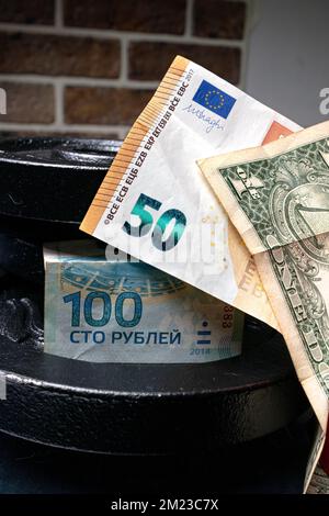 Russische 100 Rubel, 50 Euro und Dollar übereinander und Gewicht dahinter Stockfoto