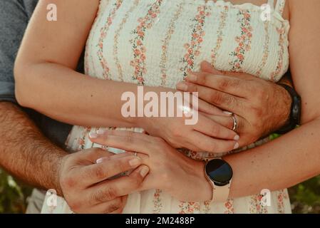 Eine Nahaufnahme eines verheirateten, reizenden Paares, das sich umarmt und ihre Ringe aufsetzt Stockfoto