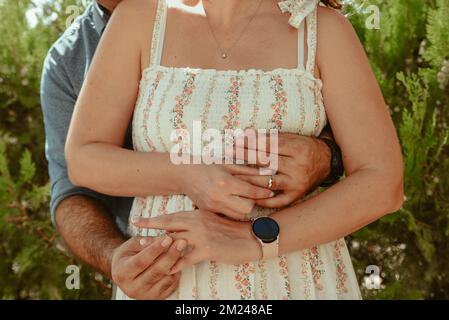 Eine Nahaufnahme eines verheirateten, reizenden Paares, das sich umarmt und ihre Ringe aufsetzt Stockfoto