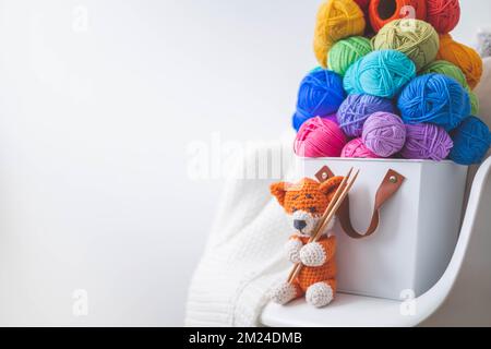 Viele bunte Garne zum Stricken und Häkeln in einem stilvollen Korb im scandi-Stil. Stockfoto