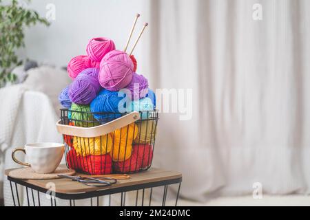 Viele bunte Garne zum Stricken und Häkeln in einem stilvollen Korb im scandi-Stil. Stockfoto