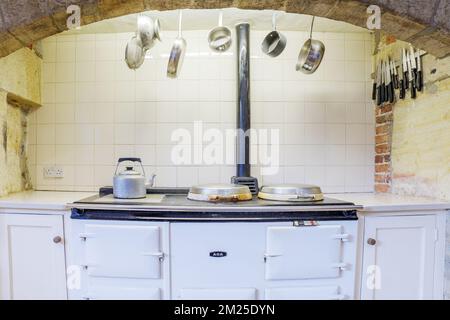 Landhausküche mit Aga-Ofen und hängenden Pfannen. Stockfoto