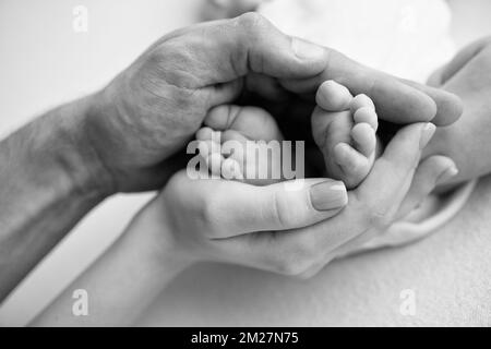 Baby Füße in den Händen von Mutter, Vater, älterer Bruder oder Schwester, Familie. Stockfoto