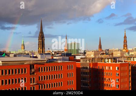 Die Kathedrale spießt über den Dächern. Hamburger Architektur mit Häusern und Dom. Regenbogen über Hamburg Stockfoto