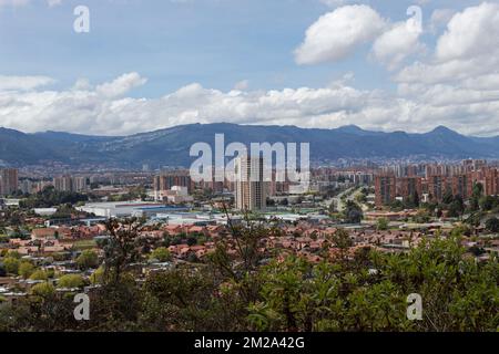 Ein Landschaftsblick auf eine moderne Stadt mit einem modernen Gebäude in der Mitte der Komposition, mit Bergen und blauem Himmel im Hintergrund. Städtisch und Stockfoto