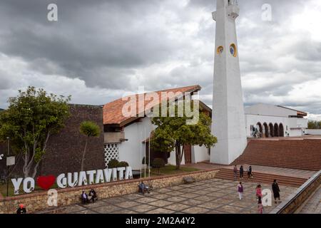 KOLUMBIEN - fantastische guatavita-Aufnahme. Ein Hauptplatz der kolumbianischen Stadt mit dem Schriftzug „ich liebe guatavita“, der Hauptkirche und dem Uhrenturm mit bewölktem Himmel Stockfoto