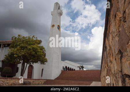 Blick auf den Hauptplatz der kolumbianischen Guatavita-Stadt mit Kirchtreppe und Uhrenturm an bewölkten Tagen Stockfoto