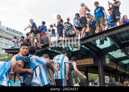 Argentine fans climb onto top of bus shelter on 9th July Avenue, Buenos Aires, Argentina to celebrate the national team reaching the final of the 2022 Stock Photo