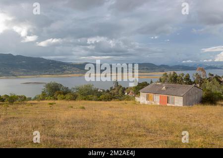 Atemberaubende Landschaft des kolumbianischen Tomine Reservoir Sees in guatavita Stadt mit einem Landhaus Berge und blauem Himmel im Hintergrund am Nachmittag goldenes h Stockfoto