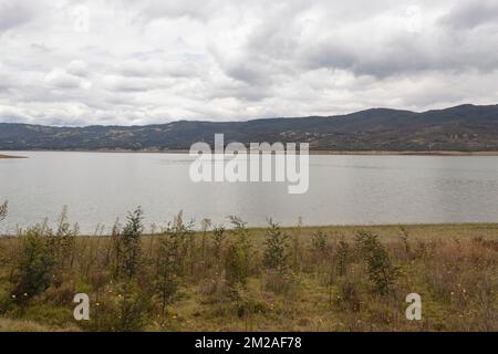 Wunderschöne Sommerszene mit blauem See, der den Himmel reflektiert, und grünen Bergen im Hintergrund Stockfoto