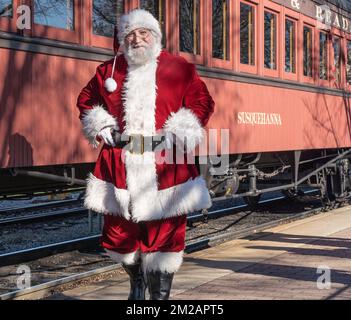 December 11, 2022-Strasburg, Pennsylvania:  Senior Gentleman dressed as Santa Clause stops to pose for a photo for a Strasburg Railroad Christmas trai Stock Photo