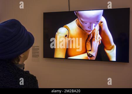 Elderly woman looking at television screen showing female android / humanoid robot at exposition about robotics and artificial intelligence / AI | Femme agée regarde androïde pendant exposition concernant la robotique et intelligence artificielle 26/11/2017 Stock Photo