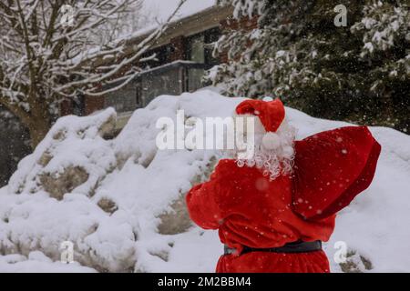 Sehen Sie den Weihnachtsmann mit einer roten Tasche voller Weihnachtsgeschenke, umgeben von weißem Schnee Stockfoto
