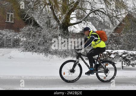 Abbildung zeigt einen Radfahrer mit gelber fluoreszierender Weste, der am Montag, den 11. Dezember 2017, auf einem Mountainbike durch den Schnee fährt, während die kalten Temperaturen in Belgien wehen. BELGA FOTO DIRK WAEM Stockfoto