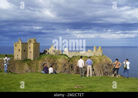 Touristen, die auf die Burg Dunnottar blicken, eine Ruine in der mittelalterlichen Festung nahe Stonehaven auf einer Klippe entlang der Nordseeküste, Aberdeenshire, Schottland, Großbritannien | Château de Dunnottar, forteresse médiévale en ruine à Stonehaven, Aberdeenshire, Ecosse, Royaume-Uni 24/05/2017 Stockfoto