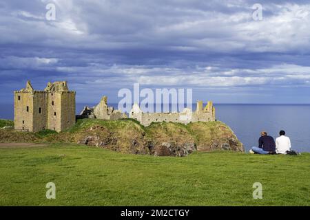 Touristen, die auf die Burg Dunnottar blicken, eine Ruine in der mittelalterlichen Festung nahe Stonehaven auf einer Klippe entlang der Nordseeküste, Aberdeenshire, Schottland, Großbritannien | Château de Dunnottar, forteresse médiévale en ruine à Stonehaven, Aberdeenshire, Ecosse, Royaume-Uni 24/05/2017 Stockfoto