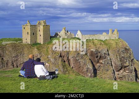 Touristen, die auf die Burg Dunnottar blicken, eine Ruine in der mittelalterlichen Festung nahe Stonehaven auf einer Klippe entlang der Nordseeküste, Aberdeenshire, Schottland, Großbritannien | Château de Dunnottar, forteresse médiévale en ruine à Stonehaven, Aberdeenshire, Ecosse, Royaume-Uni 24/05/2017 Stockfoto