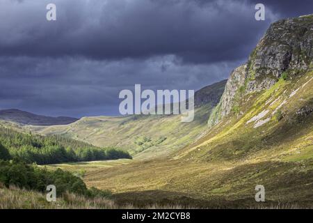 Berglandschaft mit dunklen Regenwolken über sonnigen Hügeln und Tälern in Wester Ross, Scottish Highlands, Schottland, Großbritannien | Montagnes et nuage de pluie à Wester Ross, Ecosse, Royaume-Uni 30/05/2017 Stockfoto