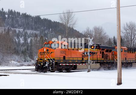 Eine BNSF-Diesel-Elektrolokomotive GE ES44DC, Triebwerk Nr. 6083, an einer Kreuzung im Schnee, nördlich von Troy, Montana. Stockfoto