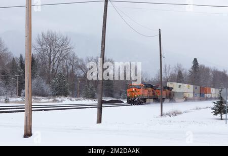 Eine BNSF-Diesel-Elektrolokomotive GE ES44DC, Triebwerk Nr. 6083, rollte die Gleise im Schnee, nördlich von Troy, Montana. Stockfoto