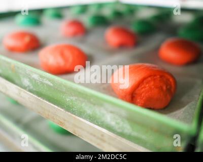 bäckerkoch, der rot-violett-gelb und grün kleine 30 Gramm farbige Brötchen für Fingerfood für Veranstaltungen macht - Catering-Zubereitung Stockfoto