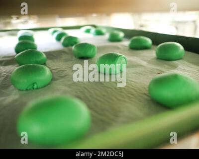 bäckerkoch, der rot-violett-gelb und grün kleine 30 Gramm farbige Brötchen für Fingerfood für Veranstaltungen macht - Catering-Zubereitung Stockfoto