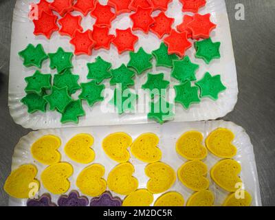 bäckermeister schneidet in der Gastronomieküche rote violettgelbe und grüne Sterne und herzförmige Buns Stockfoto