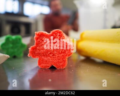 bäckermeister schneidet in der Gastronomieküche rote violettgelbe und grüne Sterne und herzförmige Buns Stockfoto