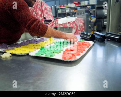 bäckermeister schneidet in der Gastronomieküche rote violettgelbe und grüne Sterne und herzförmige Buns Stockfoto