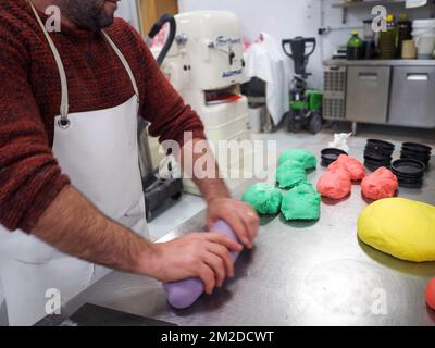 bäckerkoch, der rot-violett-gelb und grün kleine 30 Gramm farbige Brötchen für Fingerfood für Veranstaltungen macht - Catering-Zubereitung Stockfoto