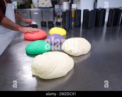 bäckerkoch, der rot-violett-gelb und grün kleine 30 Gramm farbige Brötchen für Fingerfood für Veranstaltungen macht - Catering-Zubereitung Stockfoto