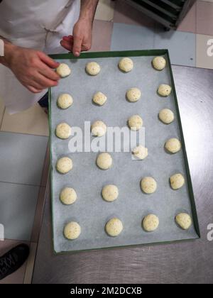 bäckerkoch, der rot-violett-gelb und grün kleine 30 Gramm farbige Brötchen für Fingerfood für Veranstaltungen macht - Catering-Zubereitung Stockfoto